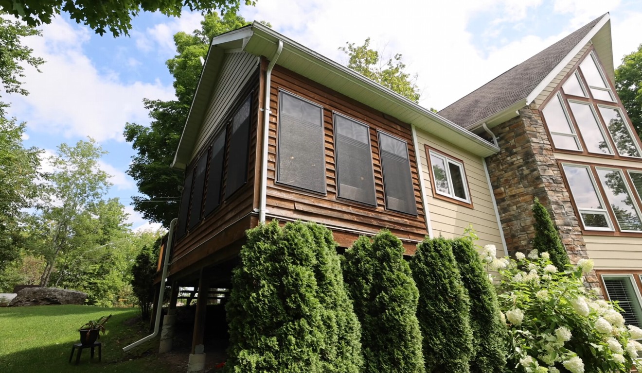 Custom sunroom with natural stone foundation and wood siding in residential setting